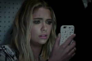 Ashley Benson staring at her phone in horror.