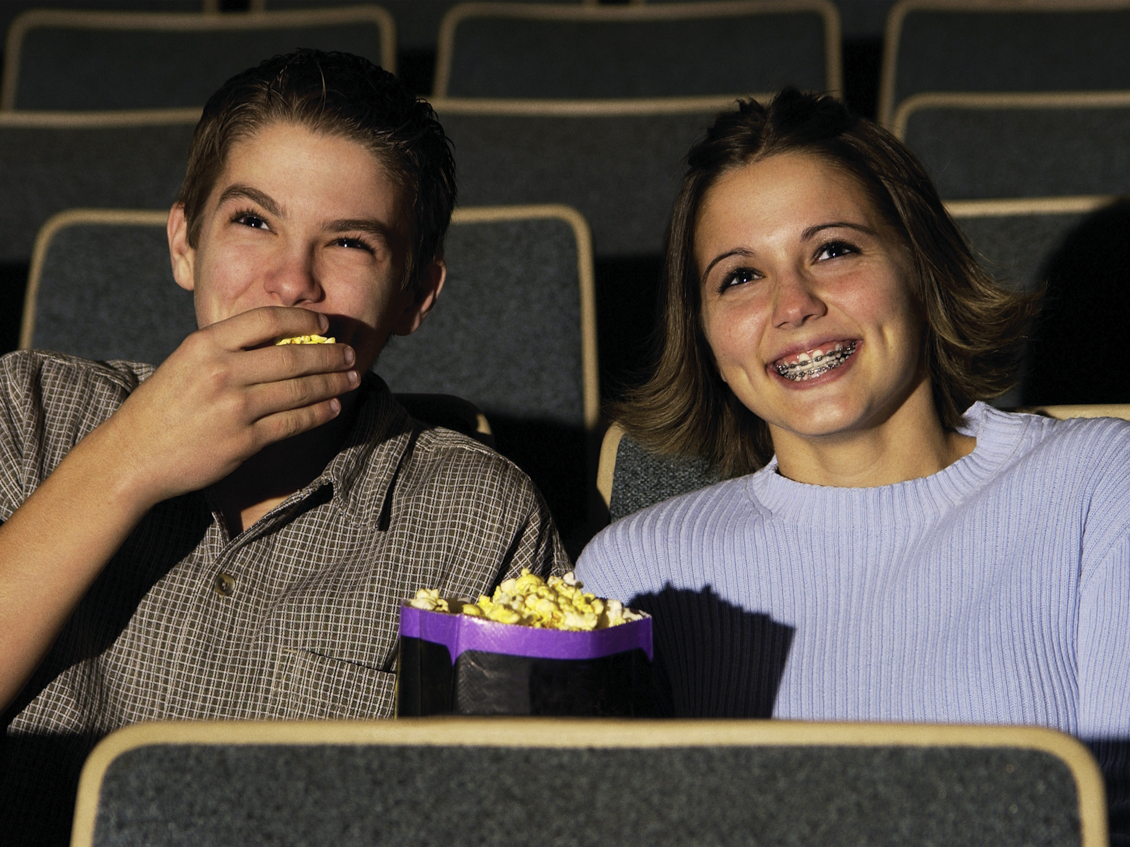 teens with braces eating popcorn in the theater