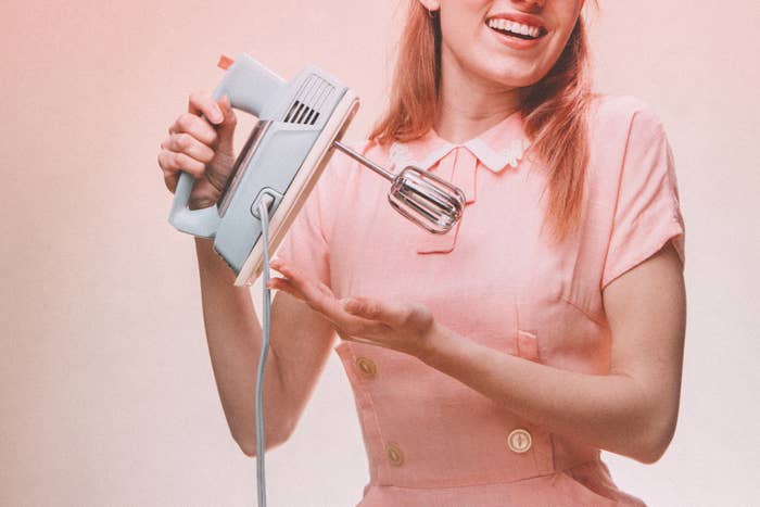 Woman dressed like a vintage homemaker holding a hand mixer