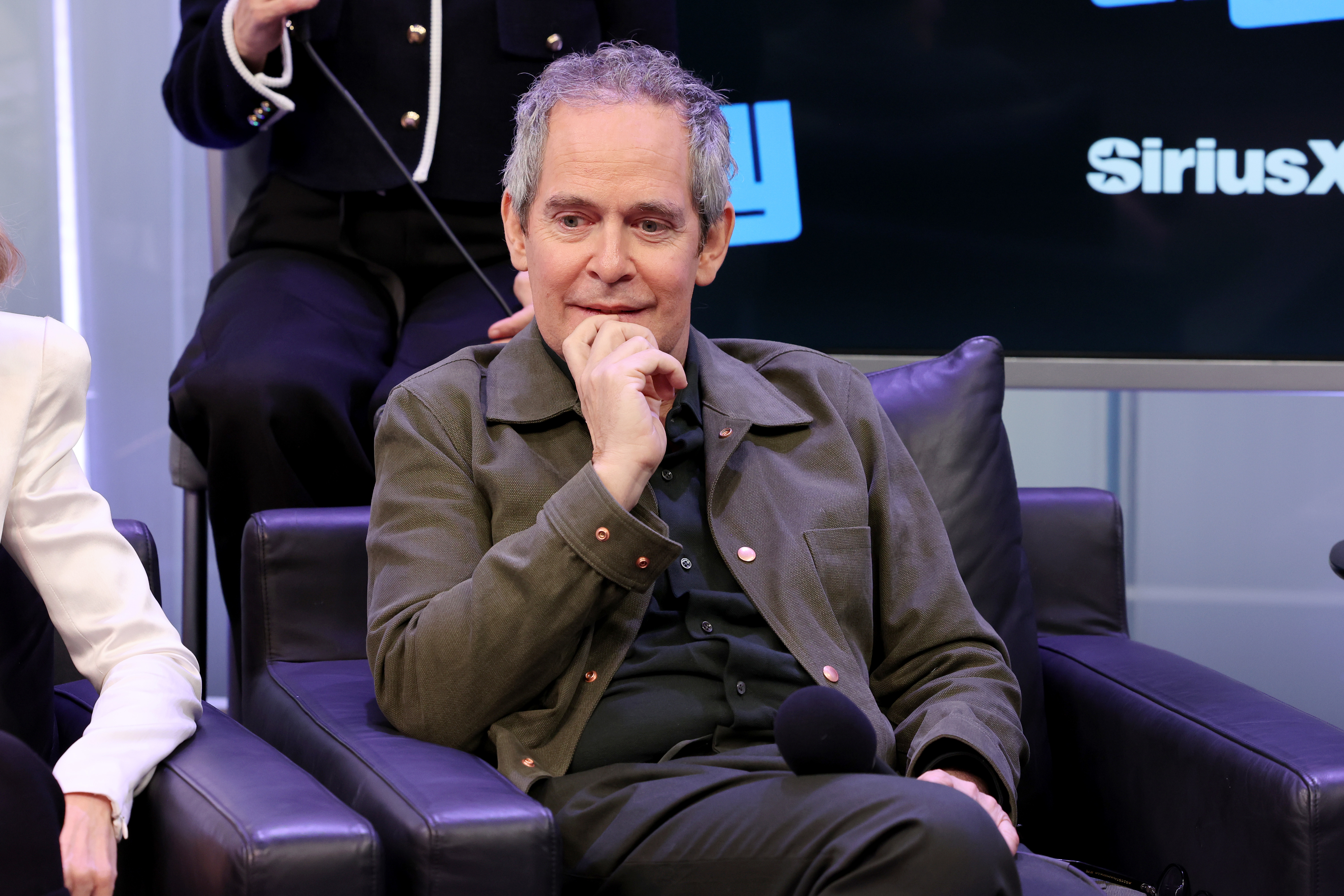 Close-up of Tom Hollander sitting and smiling at the SiriusX studios