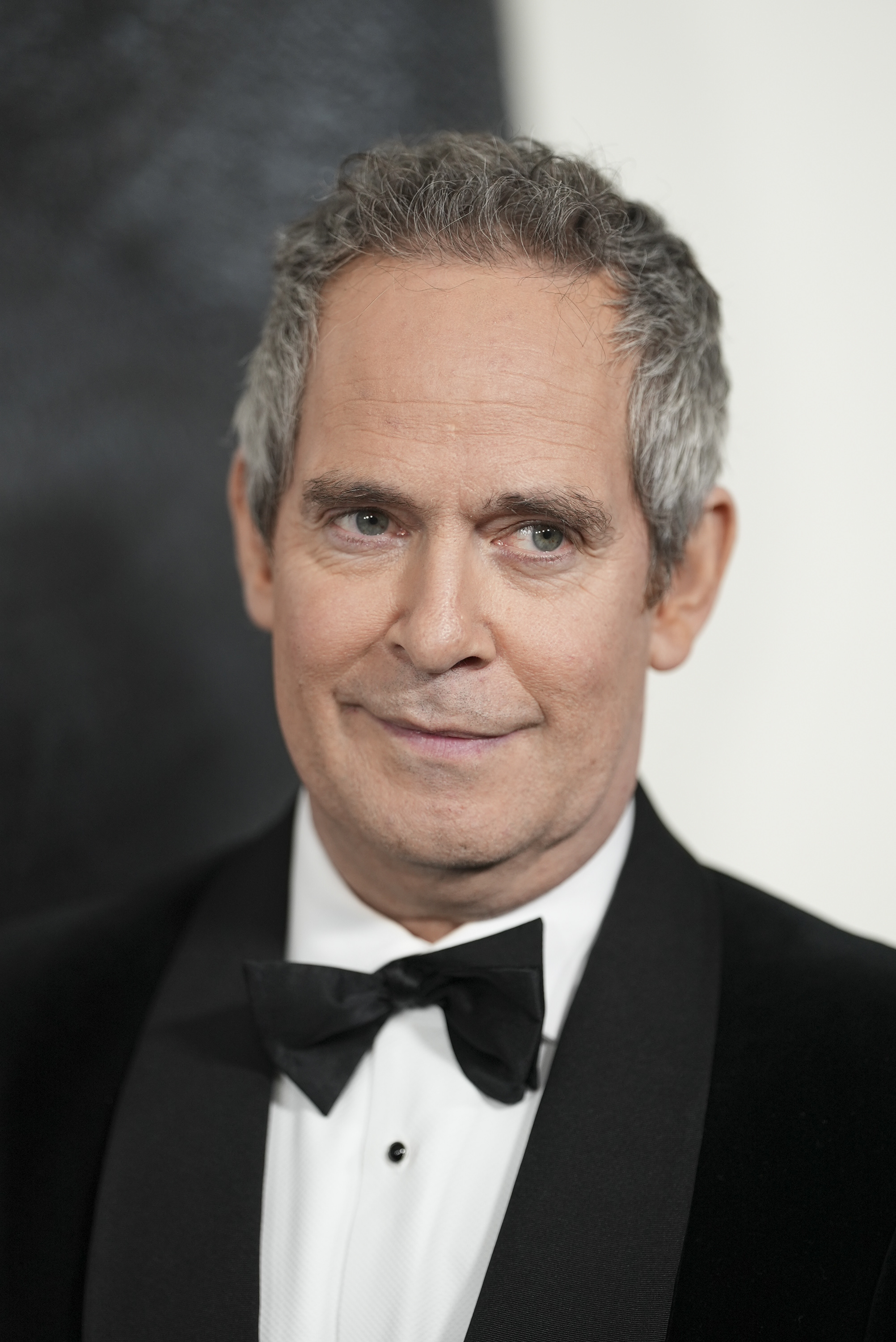 Close-up of Tom Hollander in a suit and bow tie at a media event