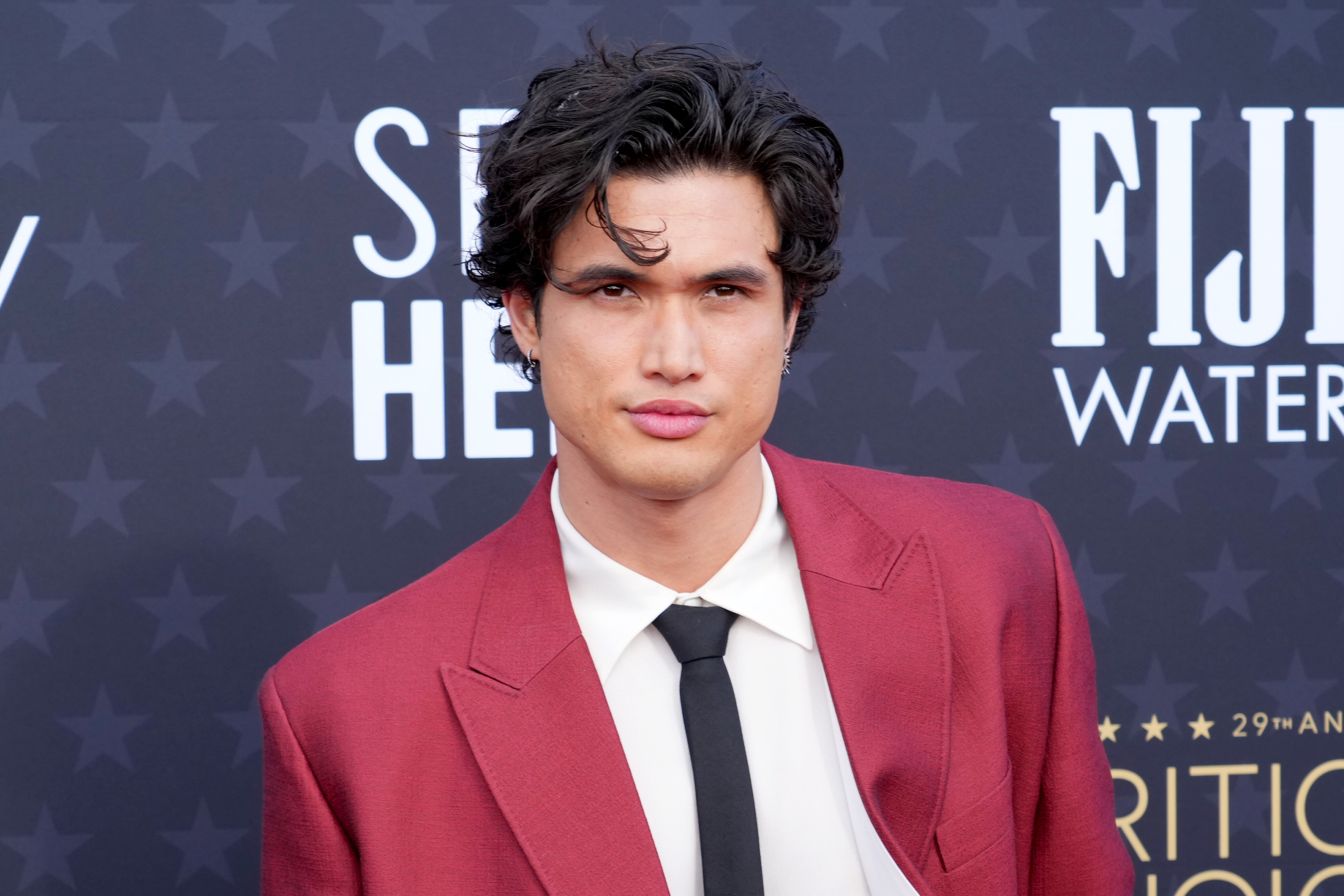 Close-up of Charles Melton in a suit and tie at a media event