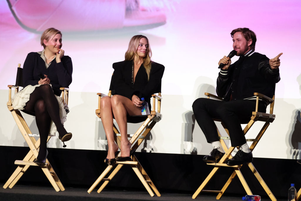 ryan, margot, and greta sitting in director&#x27;s chairs on stage
