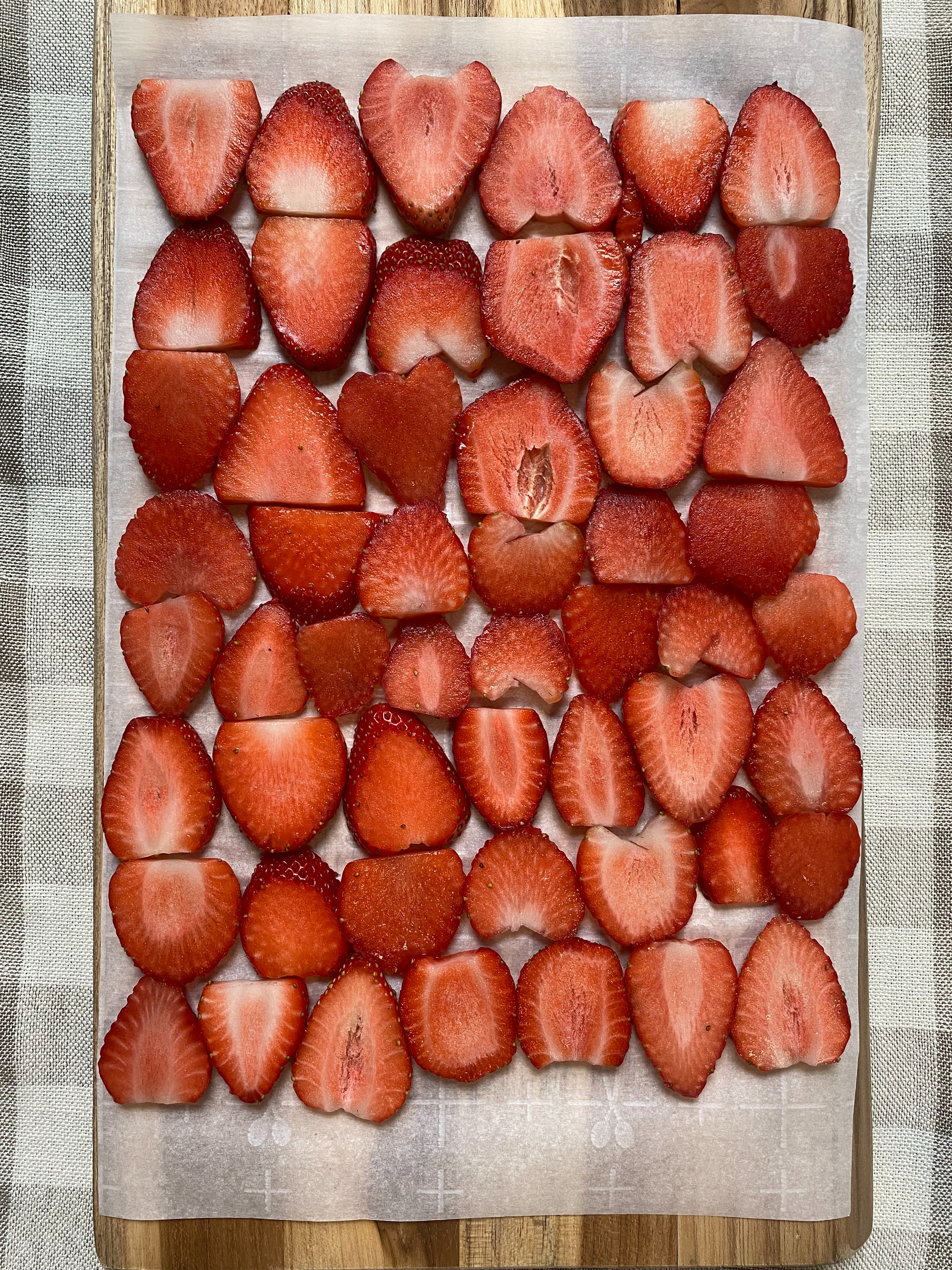 Sliced strawberries arranged on a sheet of parchment paper