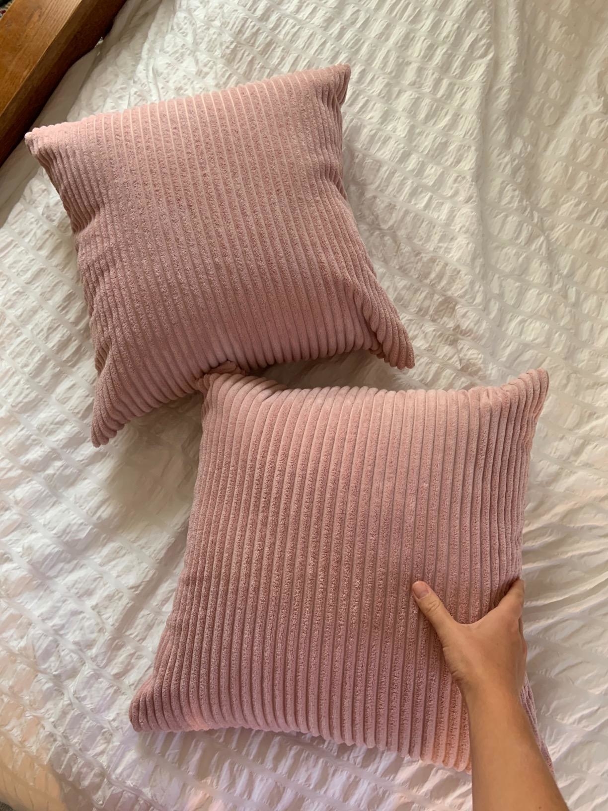 a hand touching one of the pink pillow covers