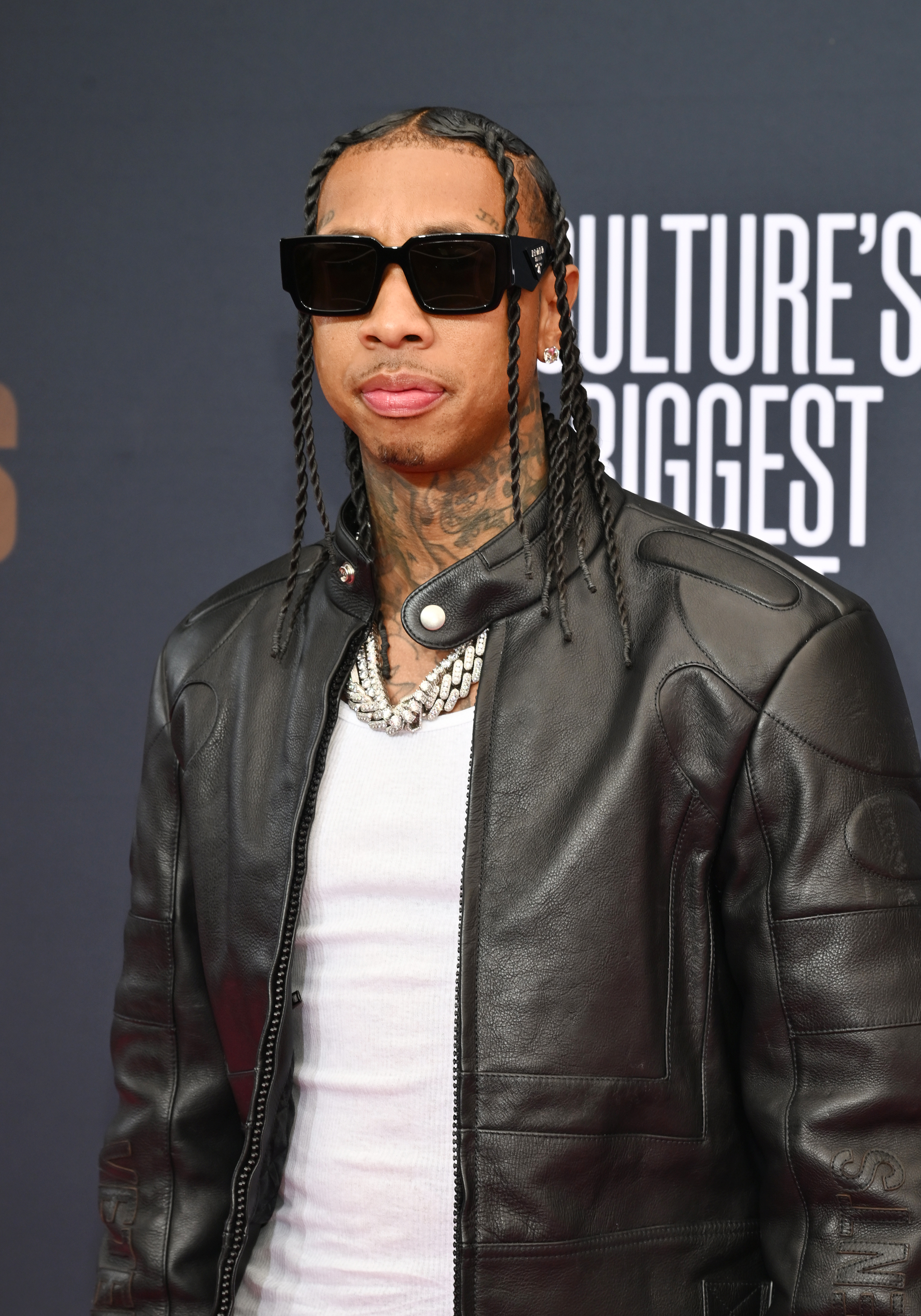 Close-up of Tyga at a media event wearing sunglasses and a leather jacket