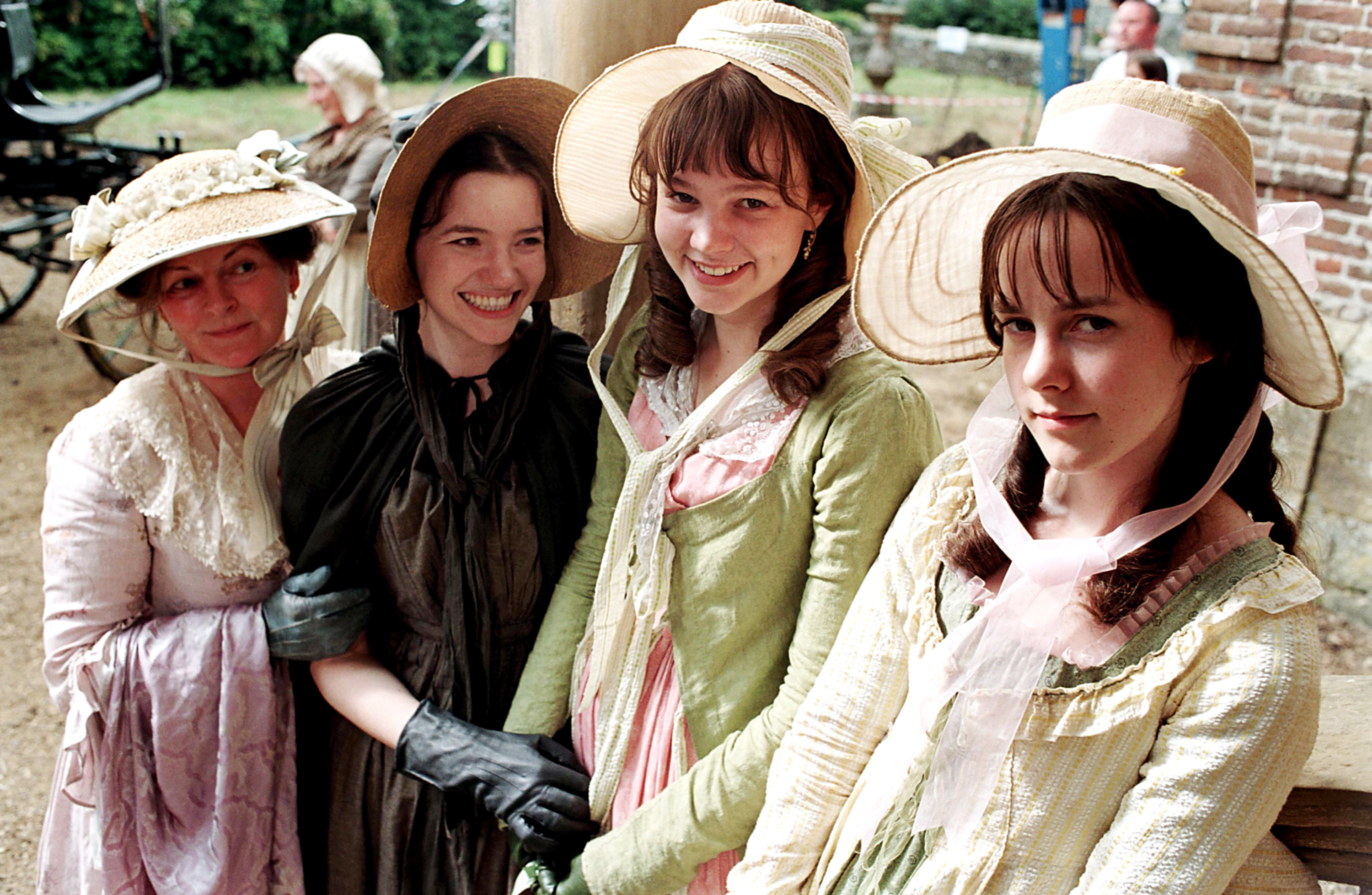 Close-up of Carey with other young women in period costumes and bonnets