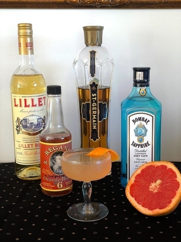 bottles of alcohol in background; in foreground, a cocktail in a coupe glass