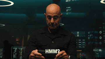 Stanley Tucci lifting his head up in interest with the caption &quot;Hmm?&quot;