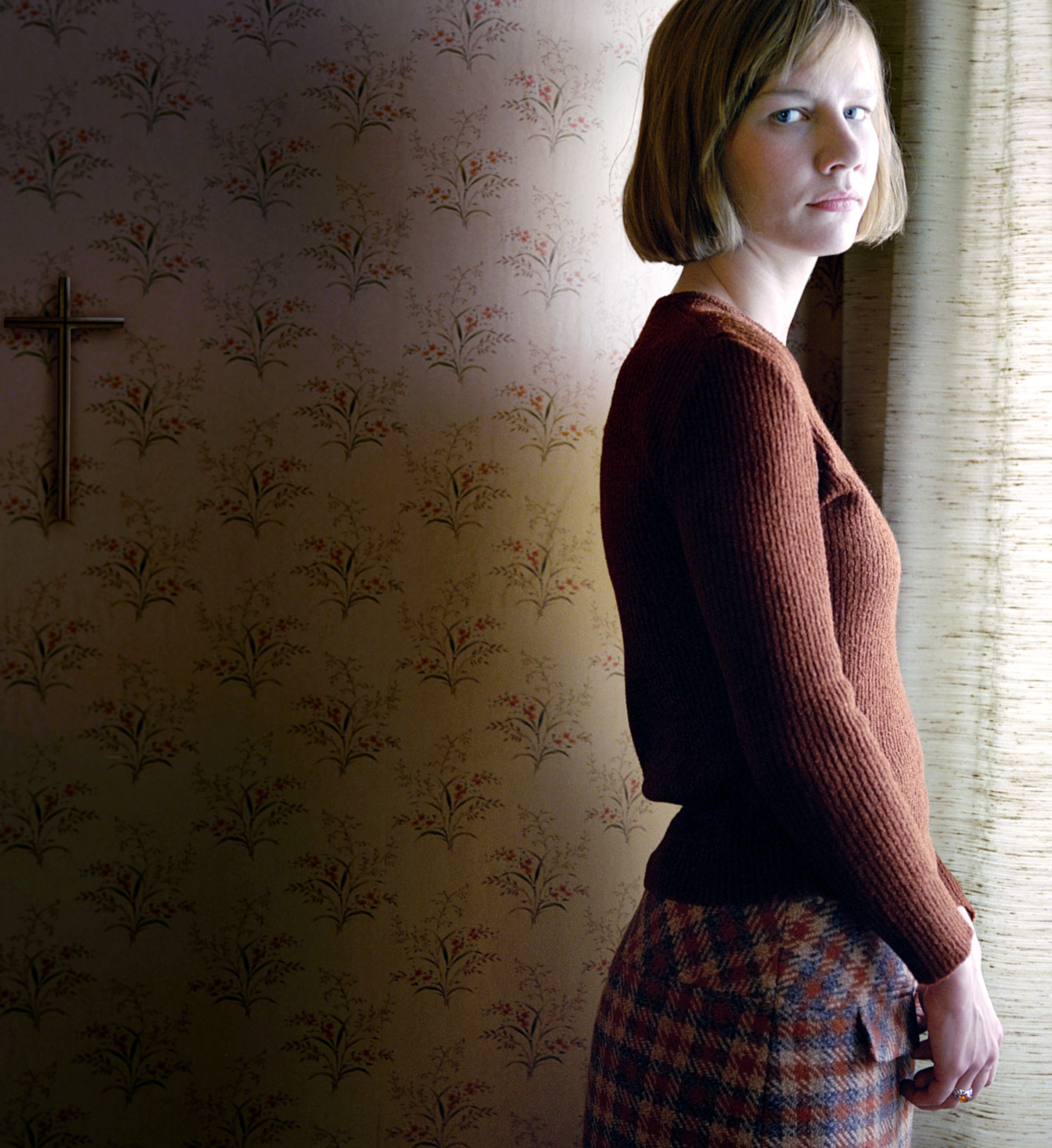 Close-up of Sandra in a sweater standing next to a window