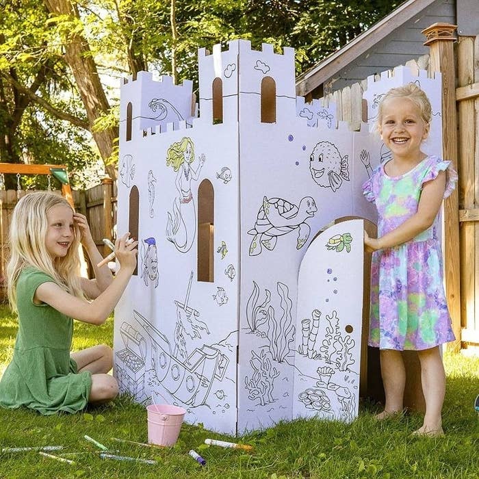 Two children color a playhouse