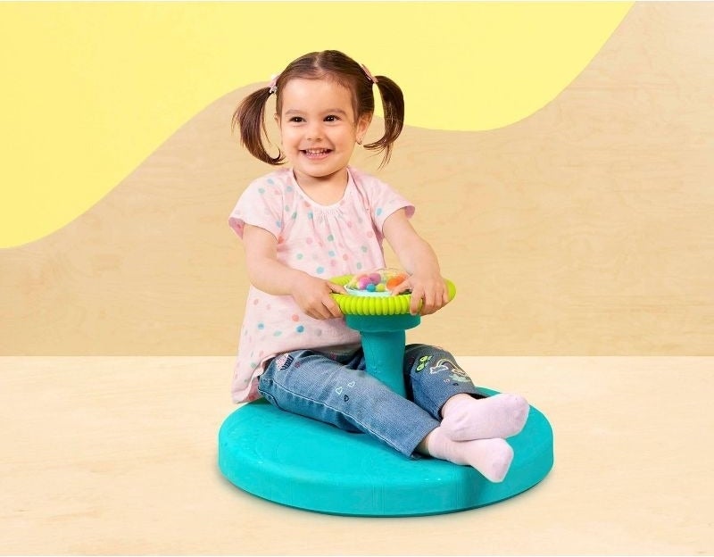 A child sits on a spinning toy