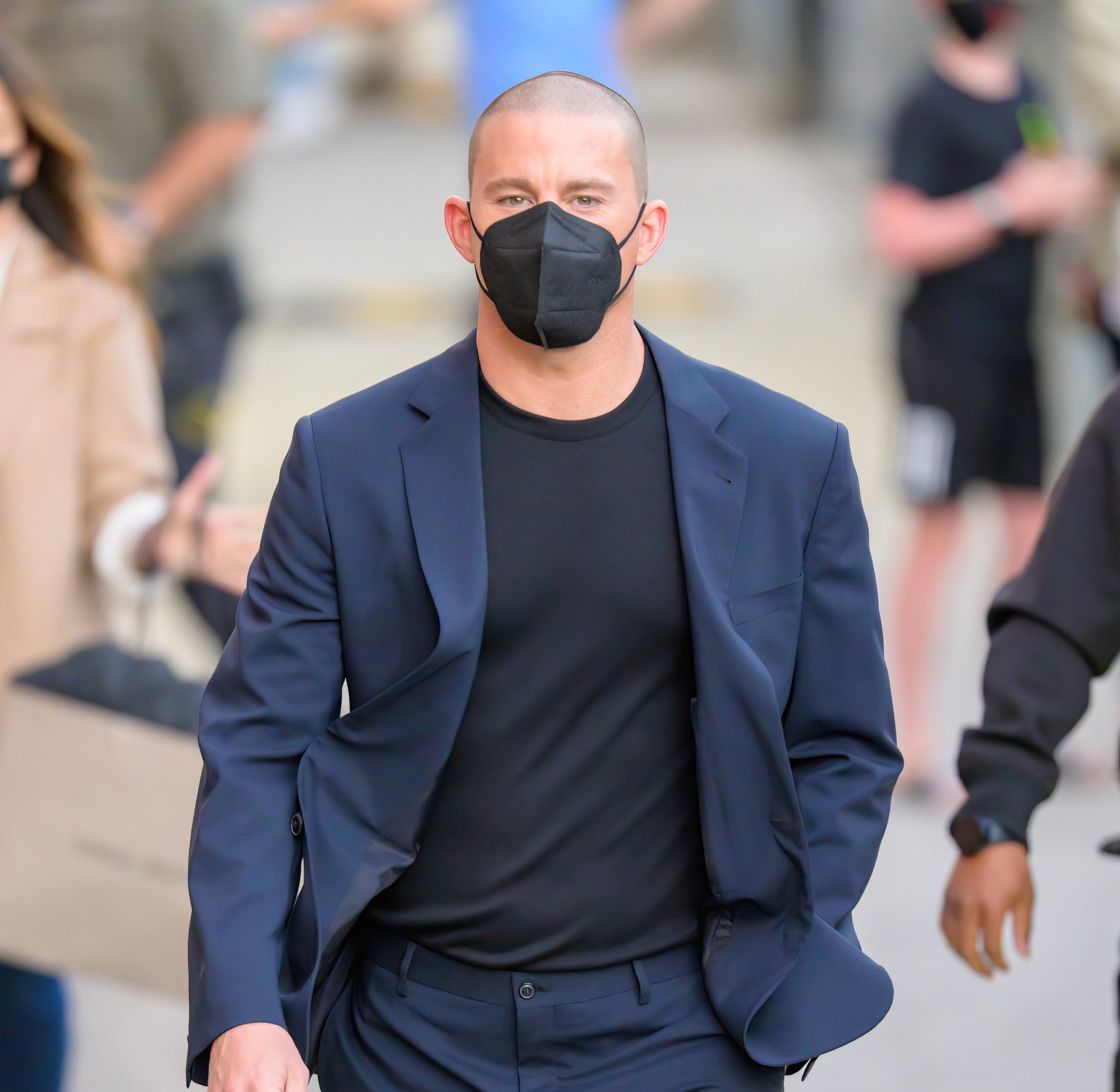 Close-up of Channing walking in a suit and wearing a KN95 mask