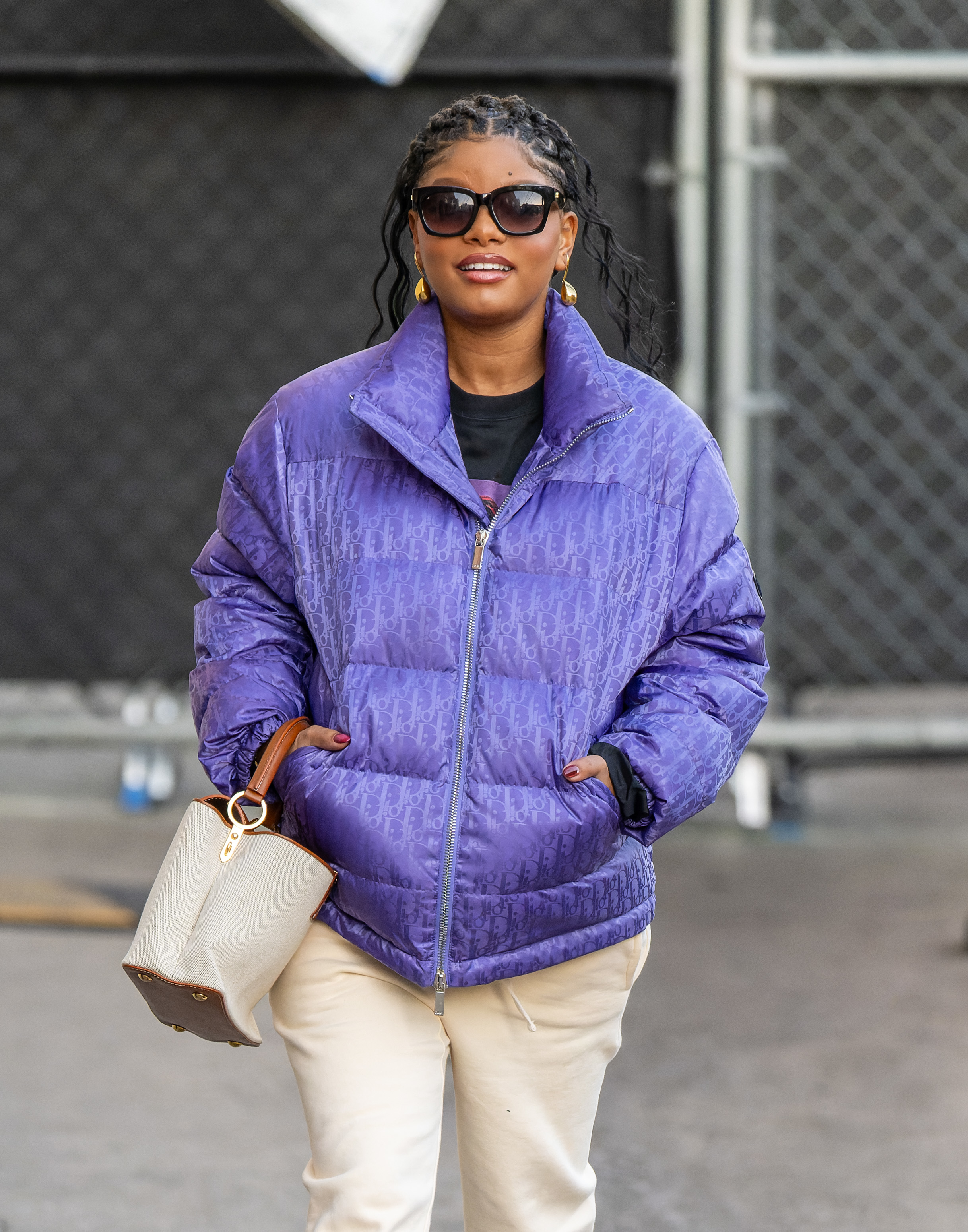 A close-up of Halle walking outside wearing a puffy zip-front jacket and pants