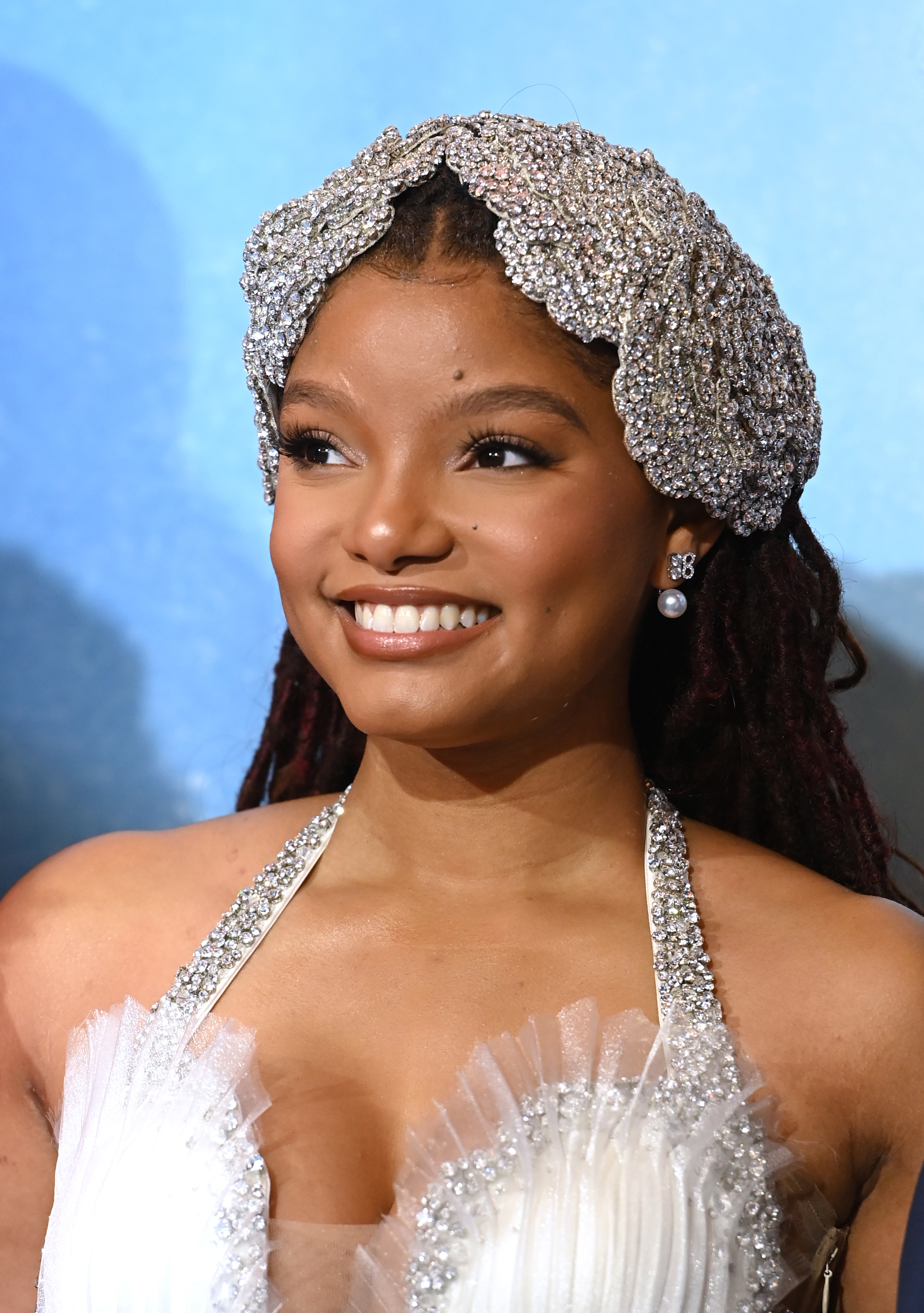 A close-up of Halle smiling in a beaded hat at a media event