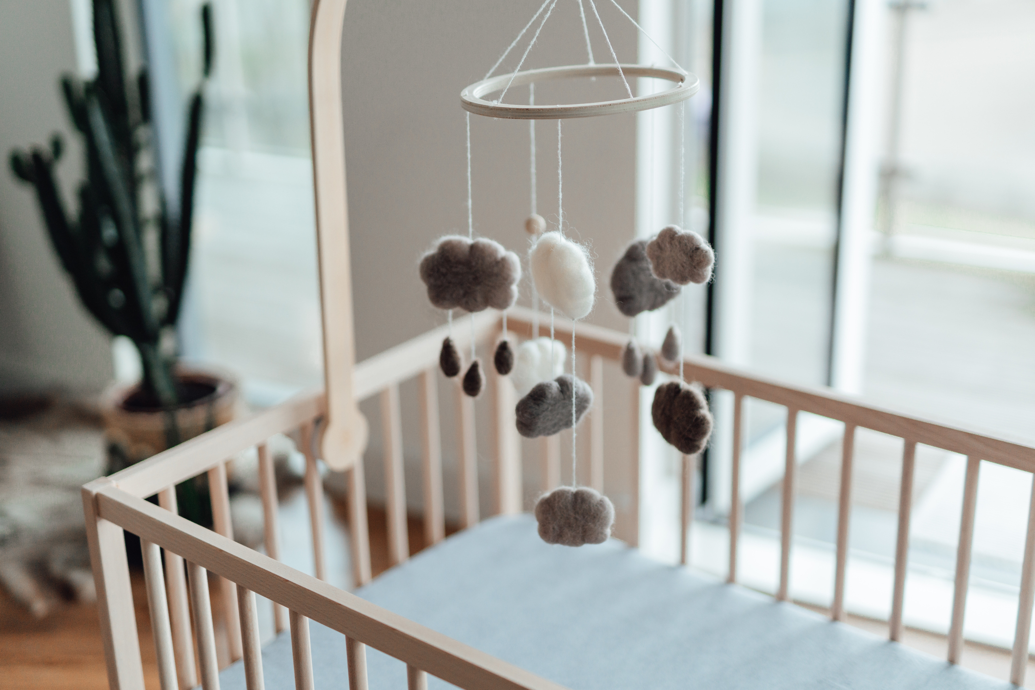 A baby&#x27;s crib bathed in light with a mobile hanging overhead