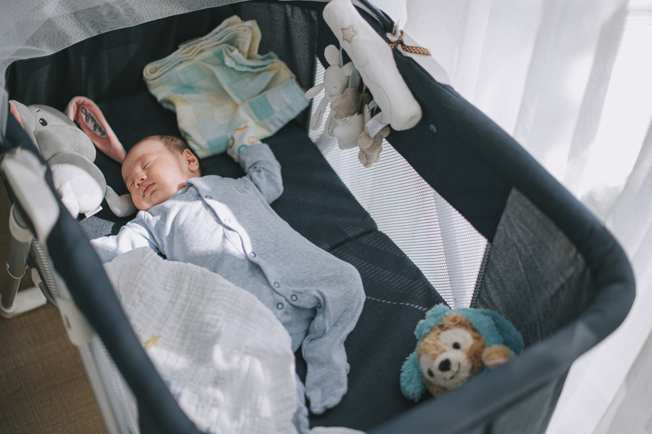 A baby asleep in a portable crib