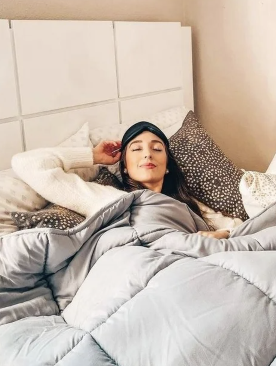 model wearing black cushioned sleep mask while laying down in bed