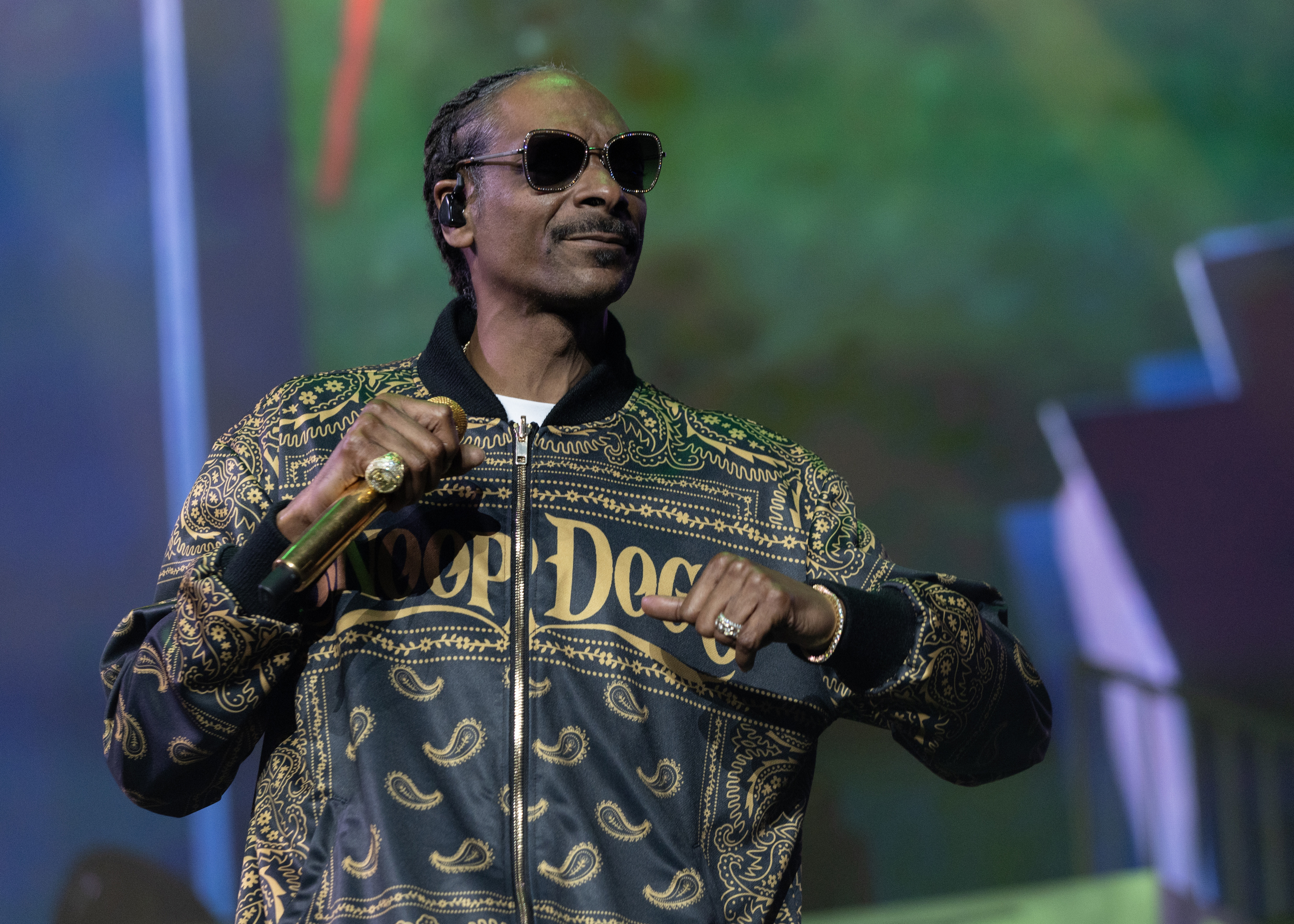 Snoop Dogg performs in a black and gold jacket