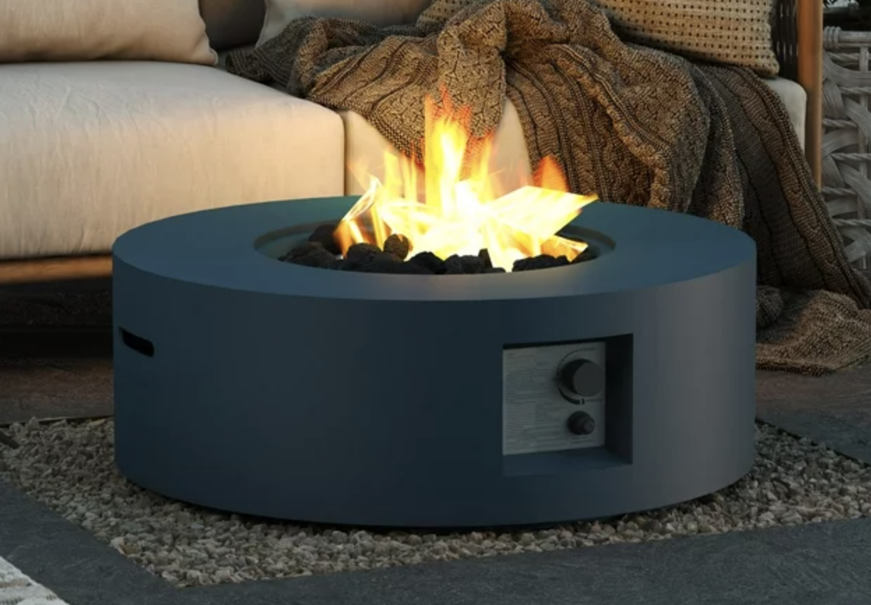 dark blue circular lit fire pit in front of white outdoor couch