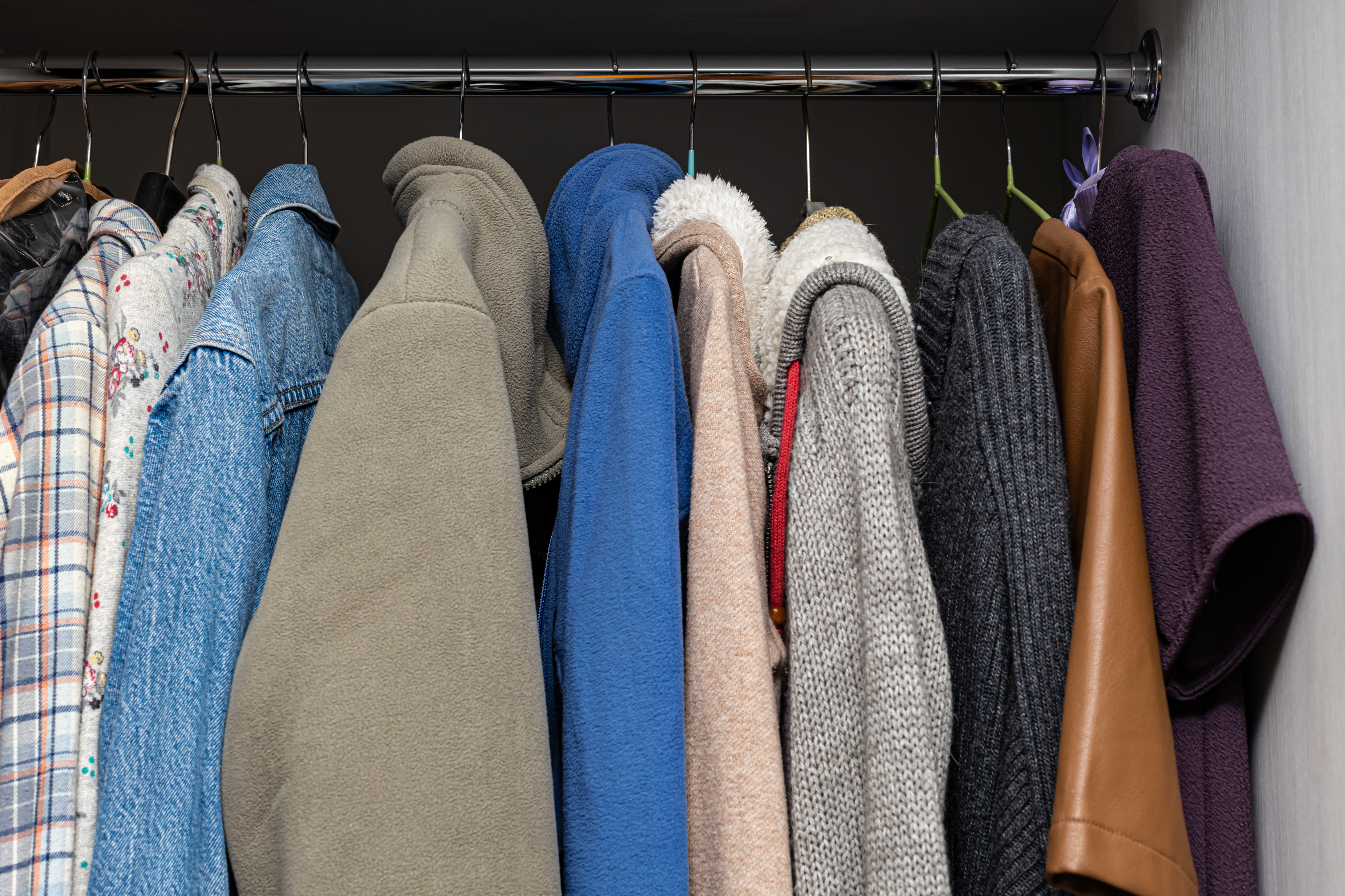 various clothes hanging on a hanger in a closet