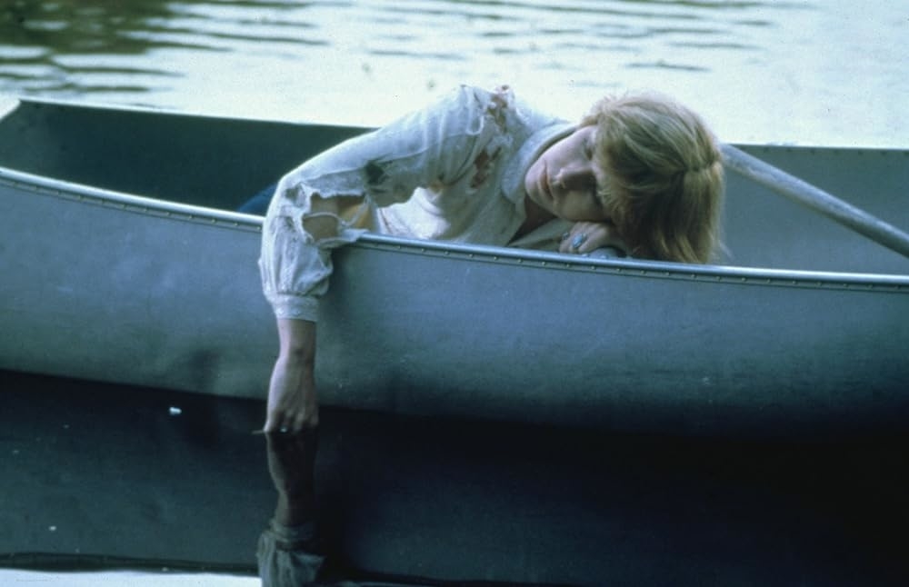 Adrienne King dipping her hands into a lake while canoeing.