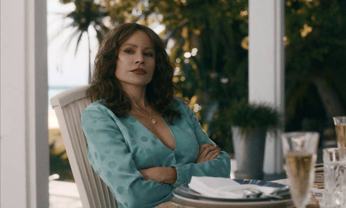 Griselda sitting at an outdoor table in a scene from the show