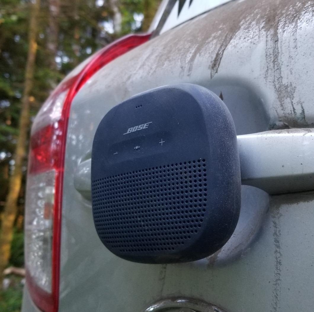 a reviewer photo of the black speaker attached to the back of a car in the woods