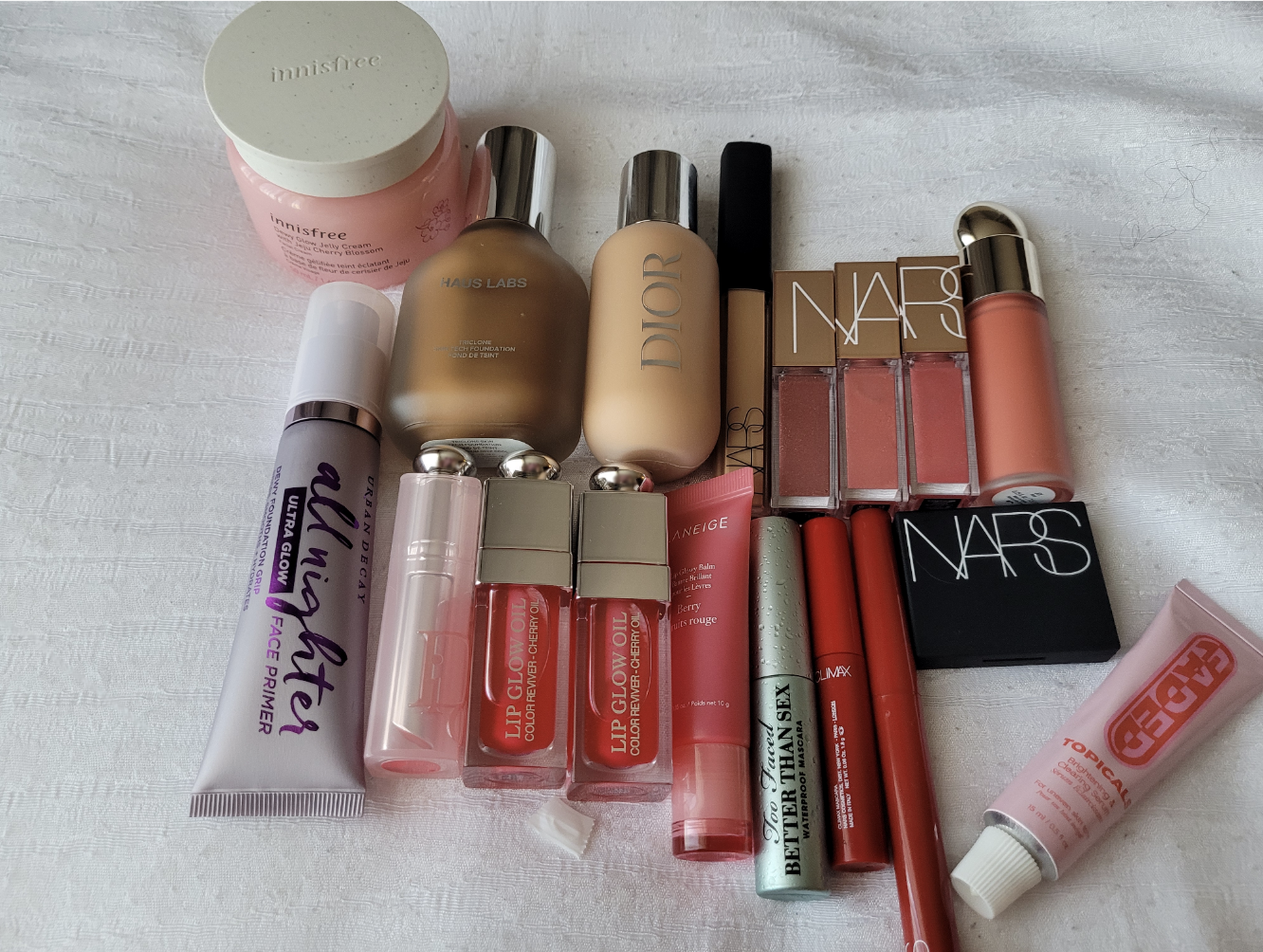 A spread of products including nars lip balms, dior lip balms, and dior foundation