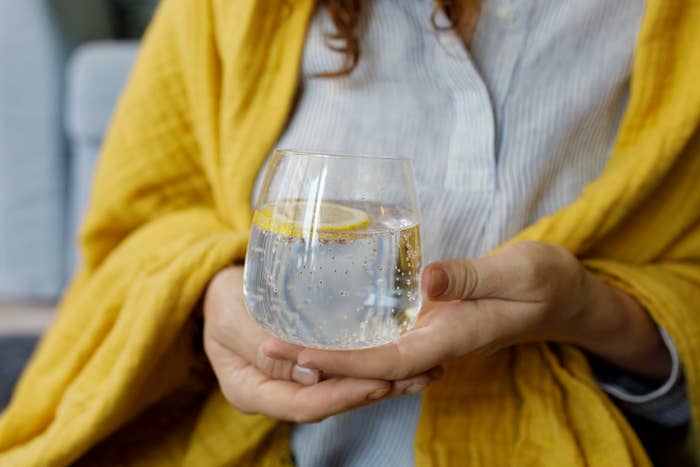 woman holding a glass of sparkling water with lemon