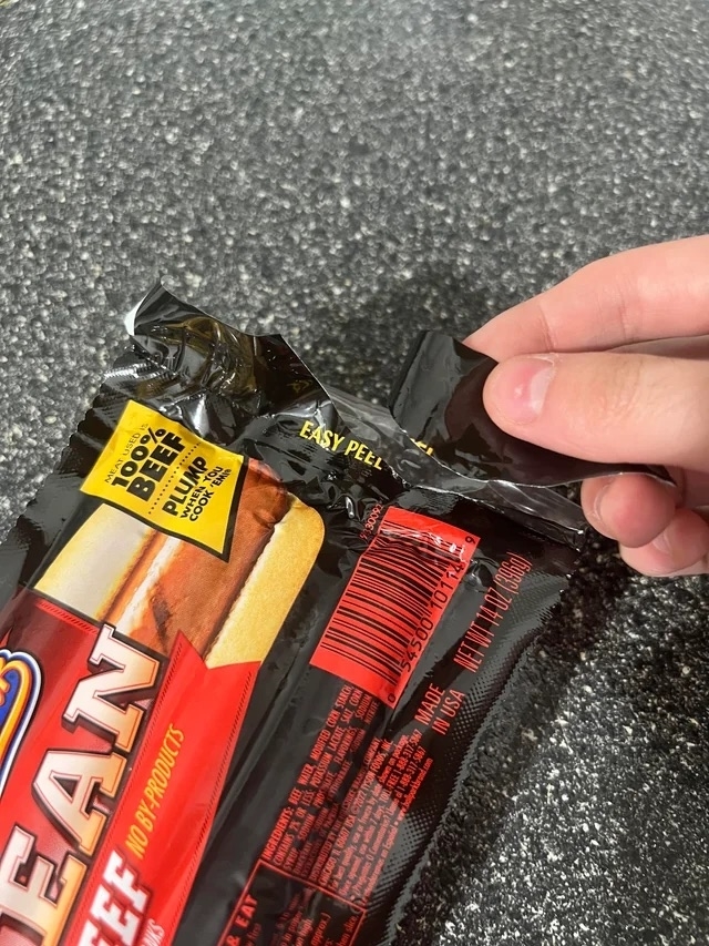 Someone tearing off a piece of a package of hot dogs labeled &#x27;Easy peel&#x27;