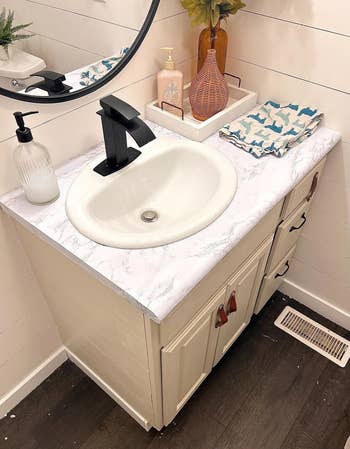 a bathroom sink counter covered in the marble adhesive