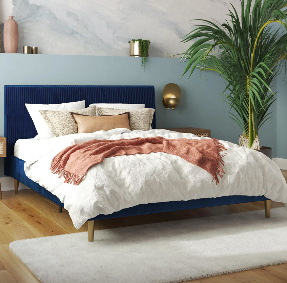 dark blue velvet bedframe with wooden peg legs in bedroom with white bedding set