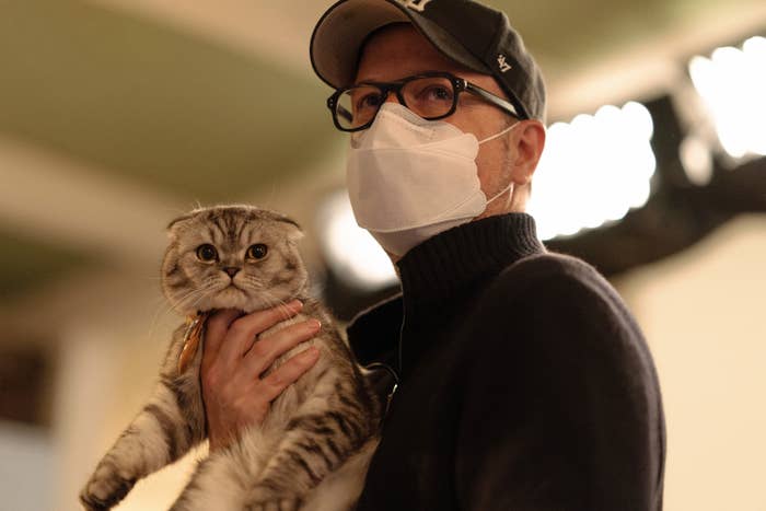 A man wearing a protective mask and holding a cat