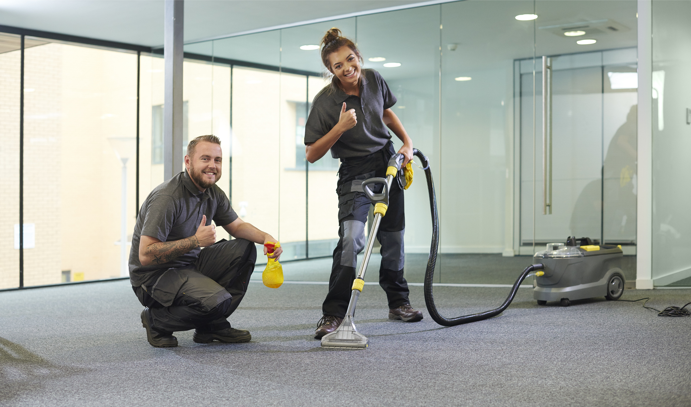 Carpet cleaners in an office building giving the thumbs-up