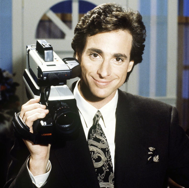 Closeup of Bob Saget holding a camera