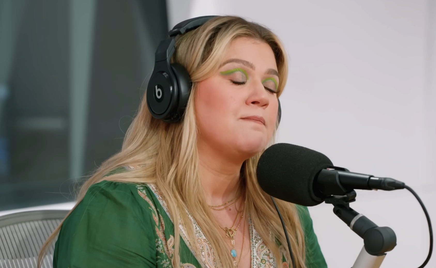 Close-up of Kelly wearing headphones and speaking into a microphone