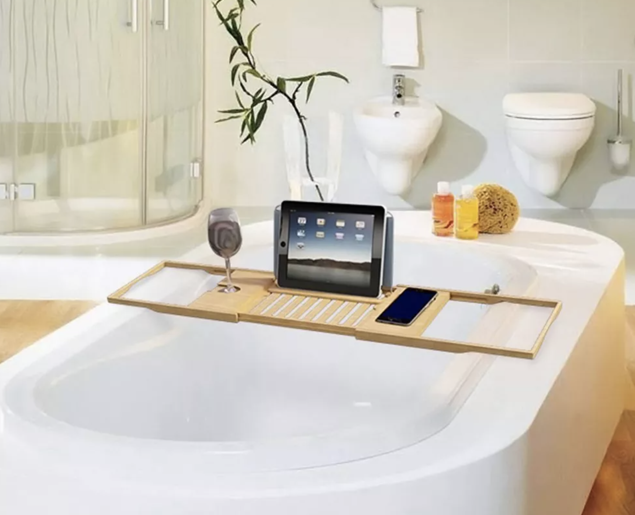 the bamboo bath caddy with a tablet and glass of wine over a white tub