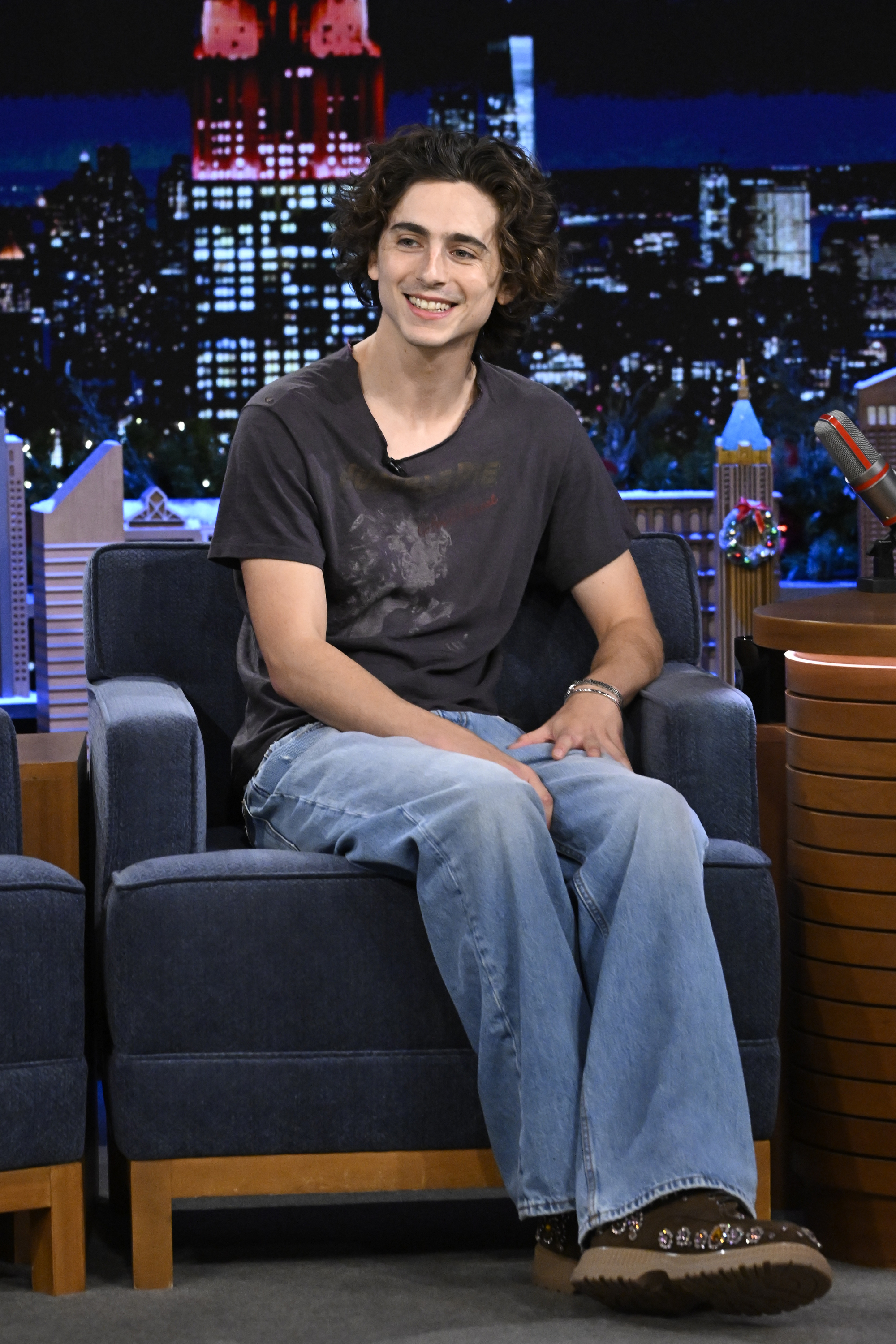 Close-up of Timothée on a talk show smiling and wearing jeans and a T-shirt