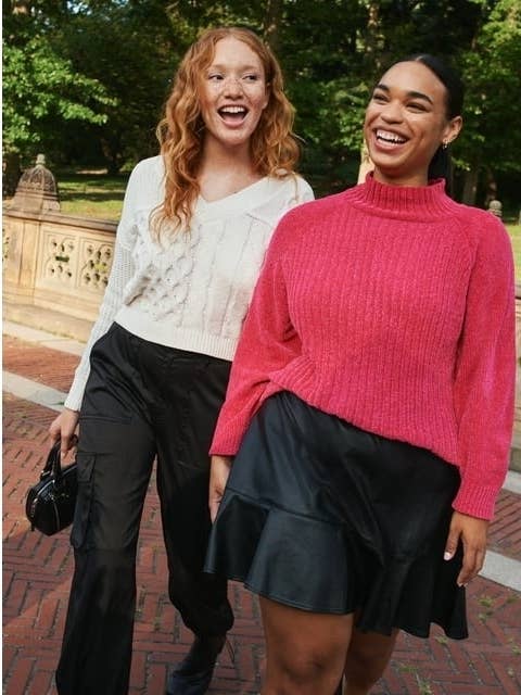 model wearing the black skirt and pink top walking with another model