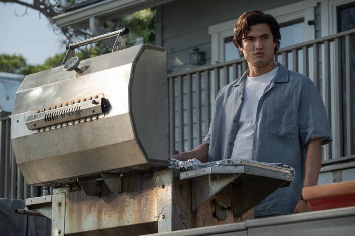 Charles Melton grilling outside in a scene from &quot;May December&quot;
