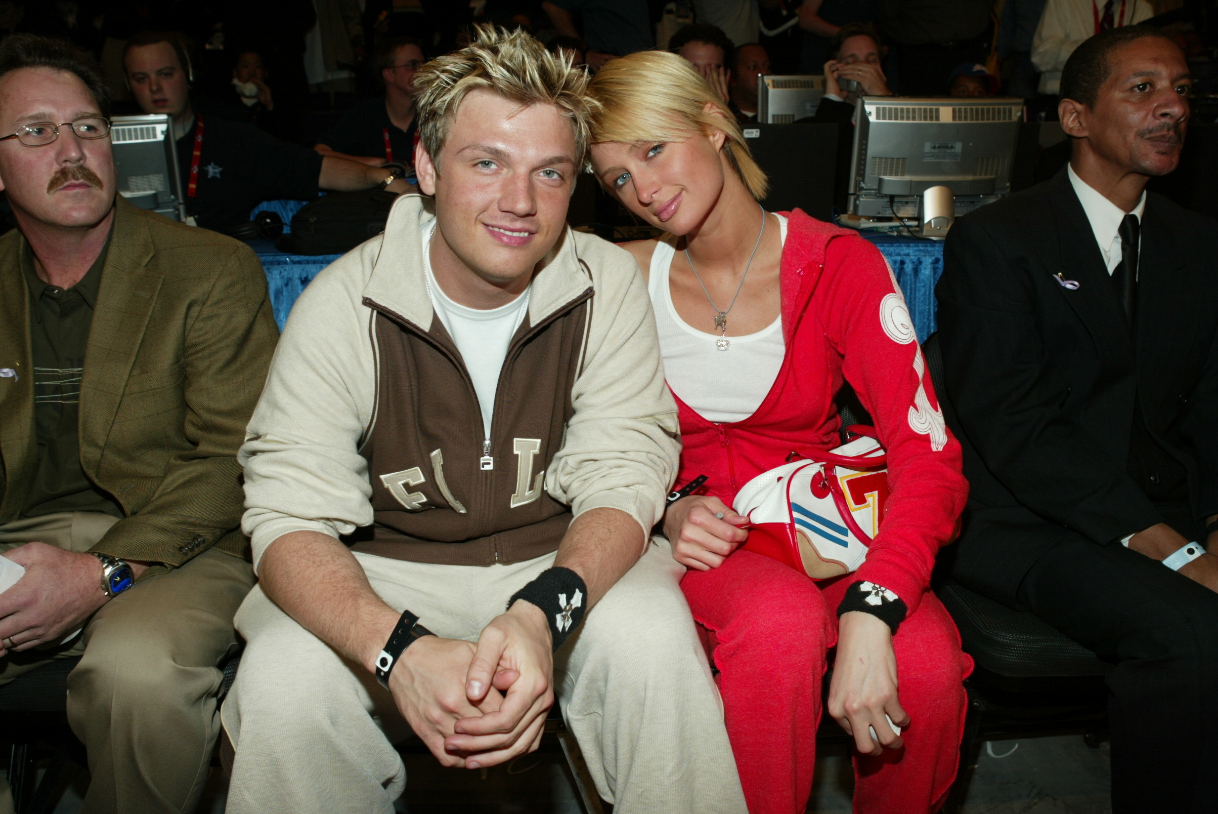 They're sitting together and smiling and wearing tracksuits