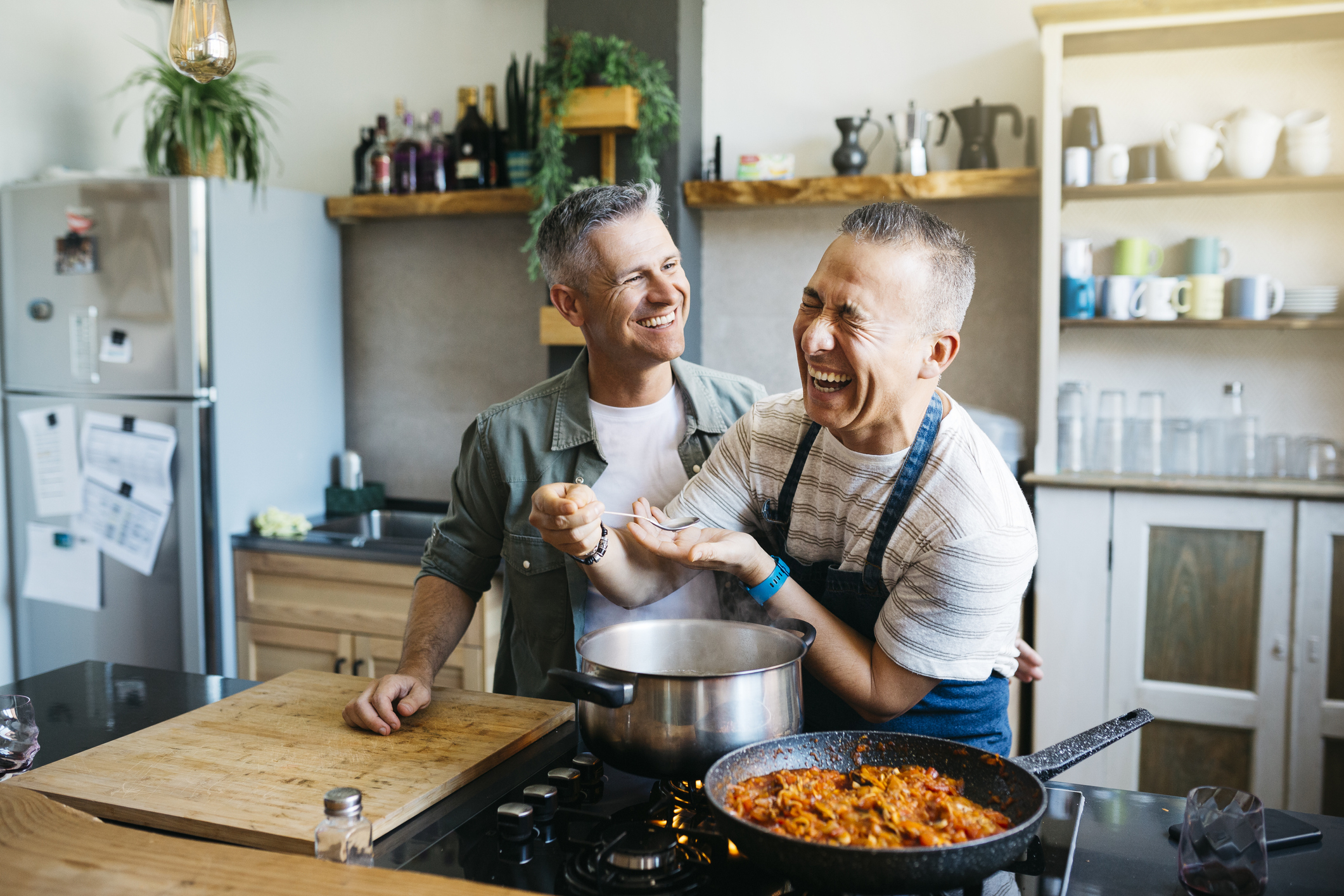 Two men laughing and cooking in the kitchen