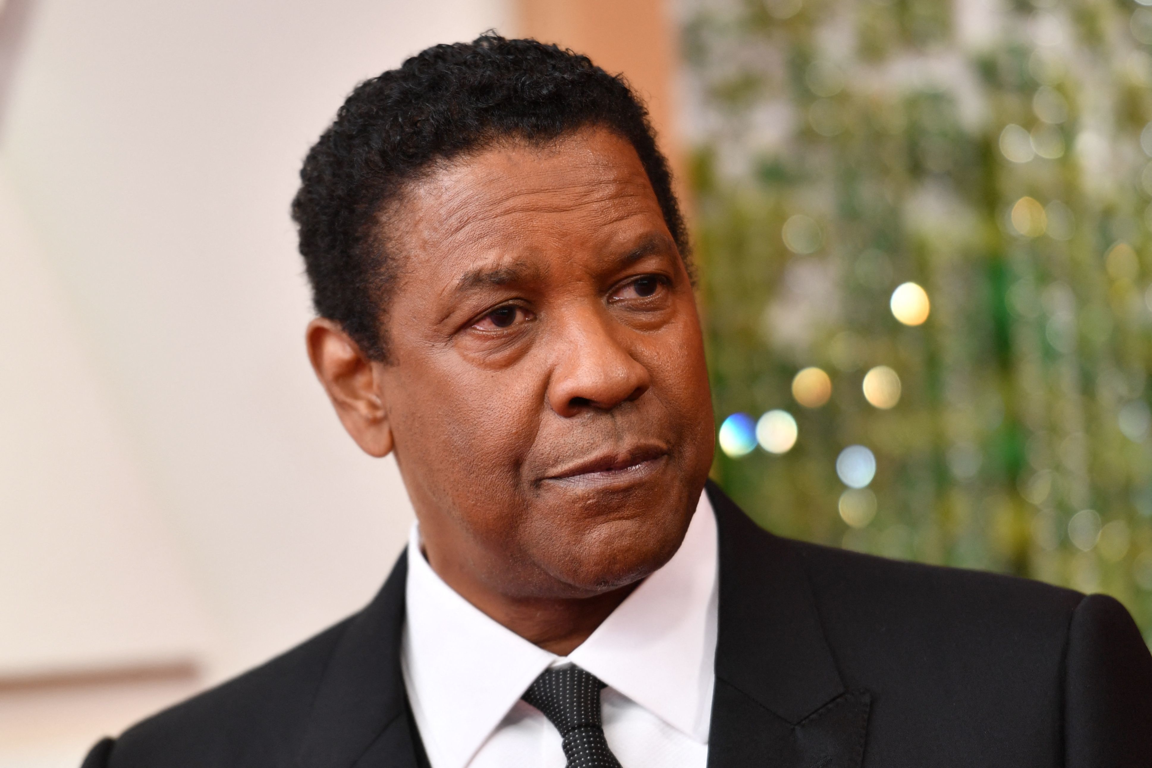 Denzel in a black suit and tie at an event
