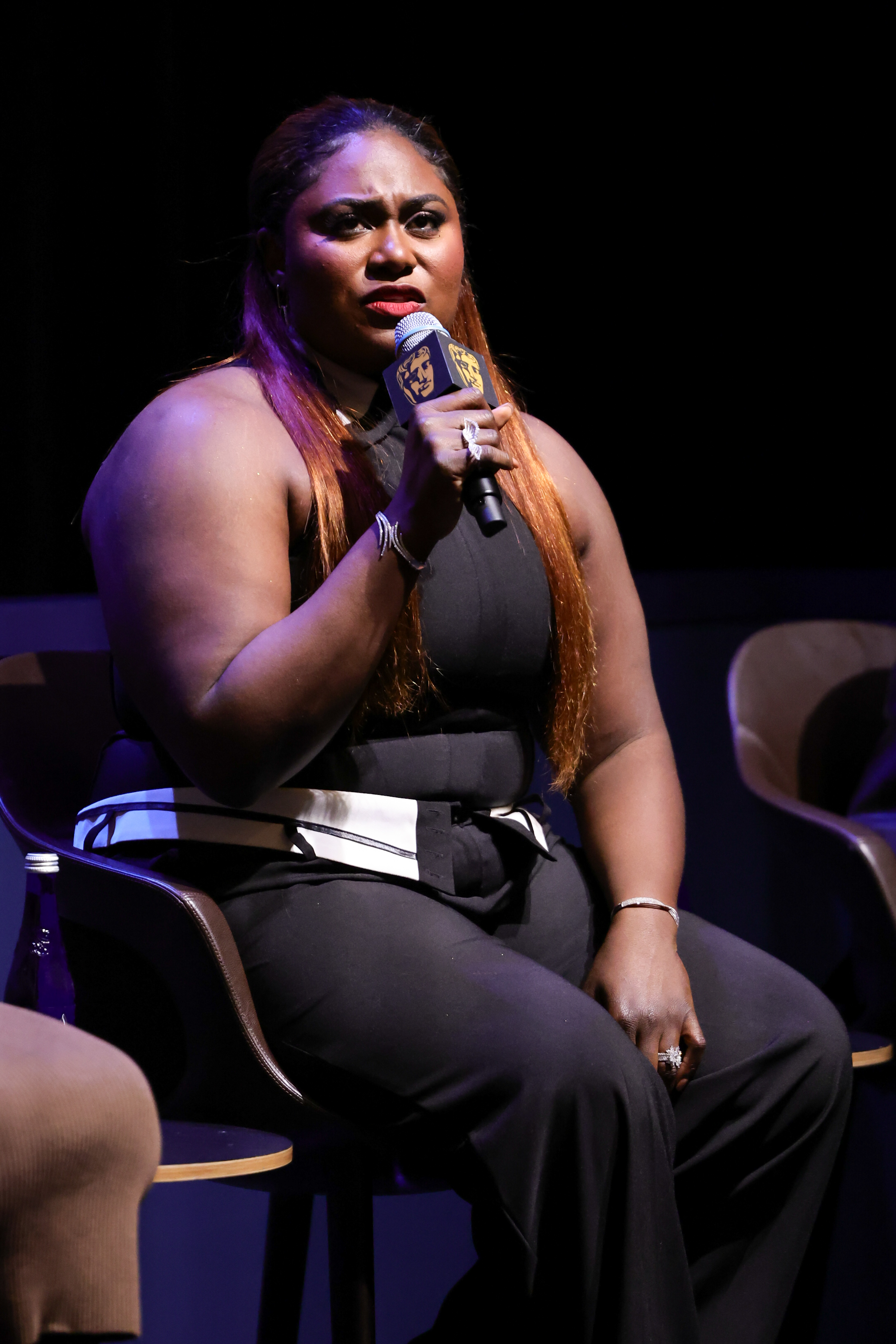 Close-up of Danielle seated onstage and holding a microphone