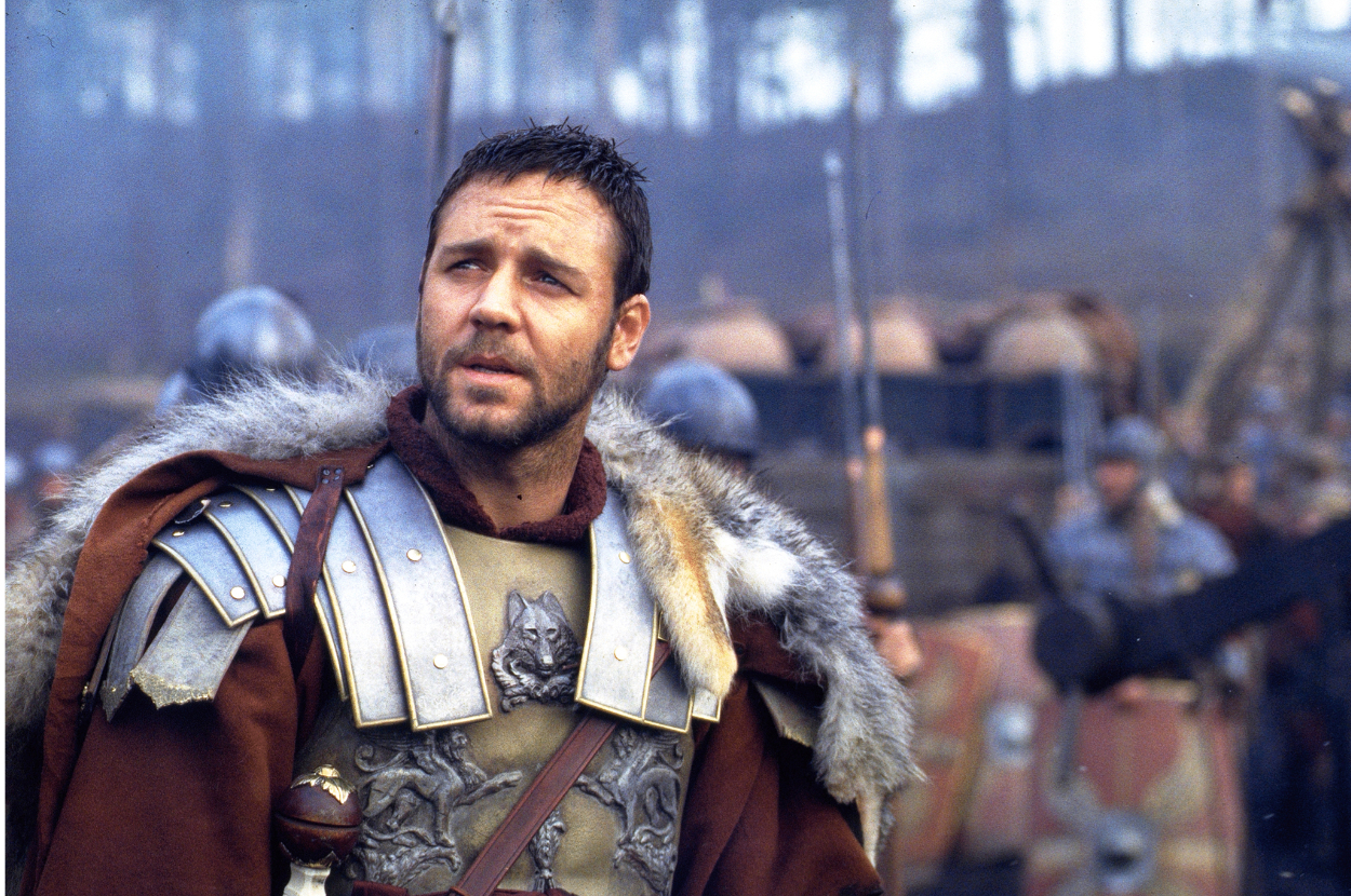 Man in medieval armor with fur collar stands pensively in a battlefield camp
