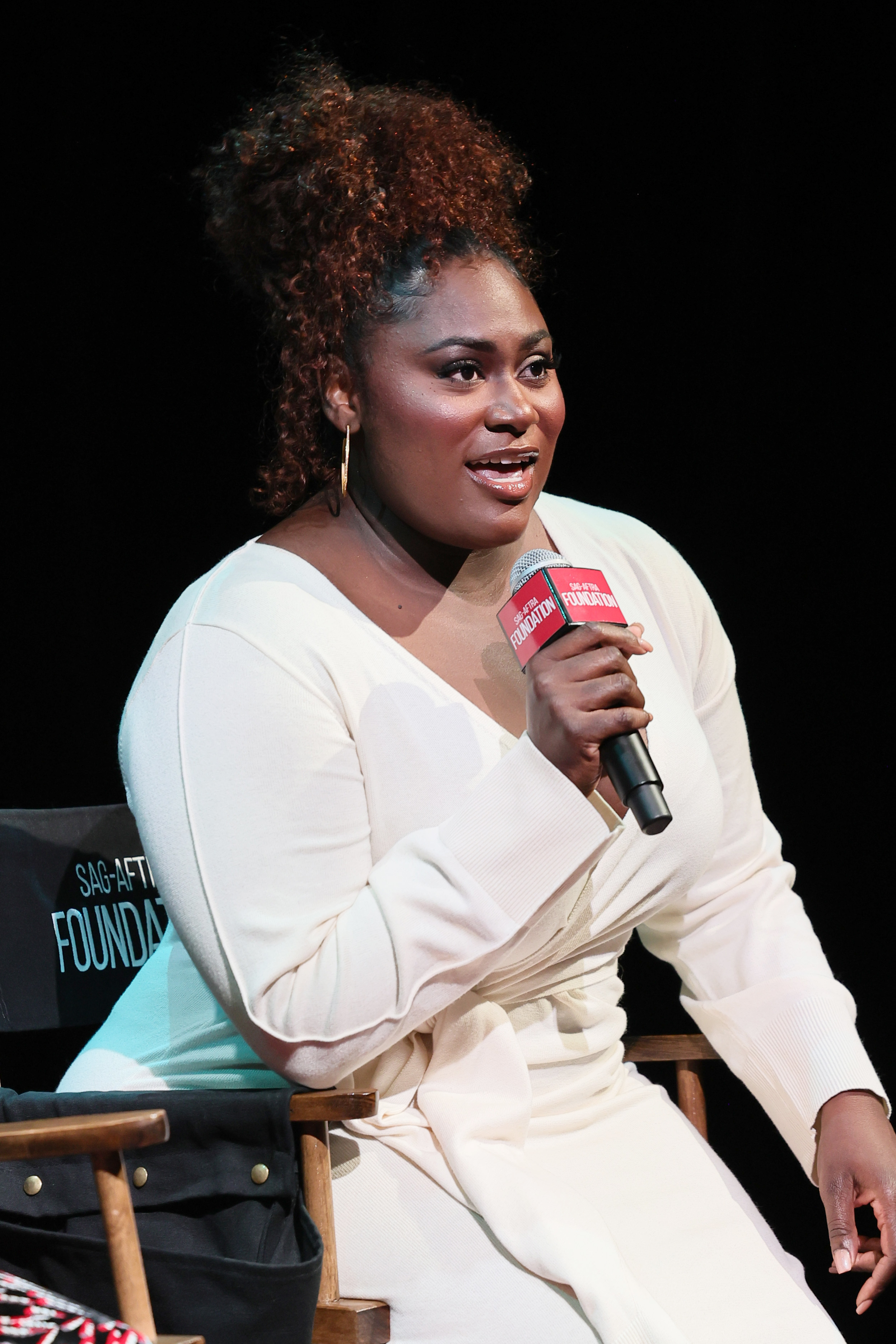 Close-up of Danielle seated onstage and holding a microphone