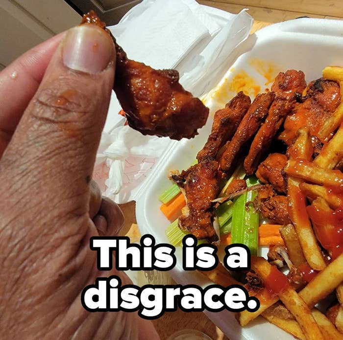 A person holding a takeout container of fries and very small wings