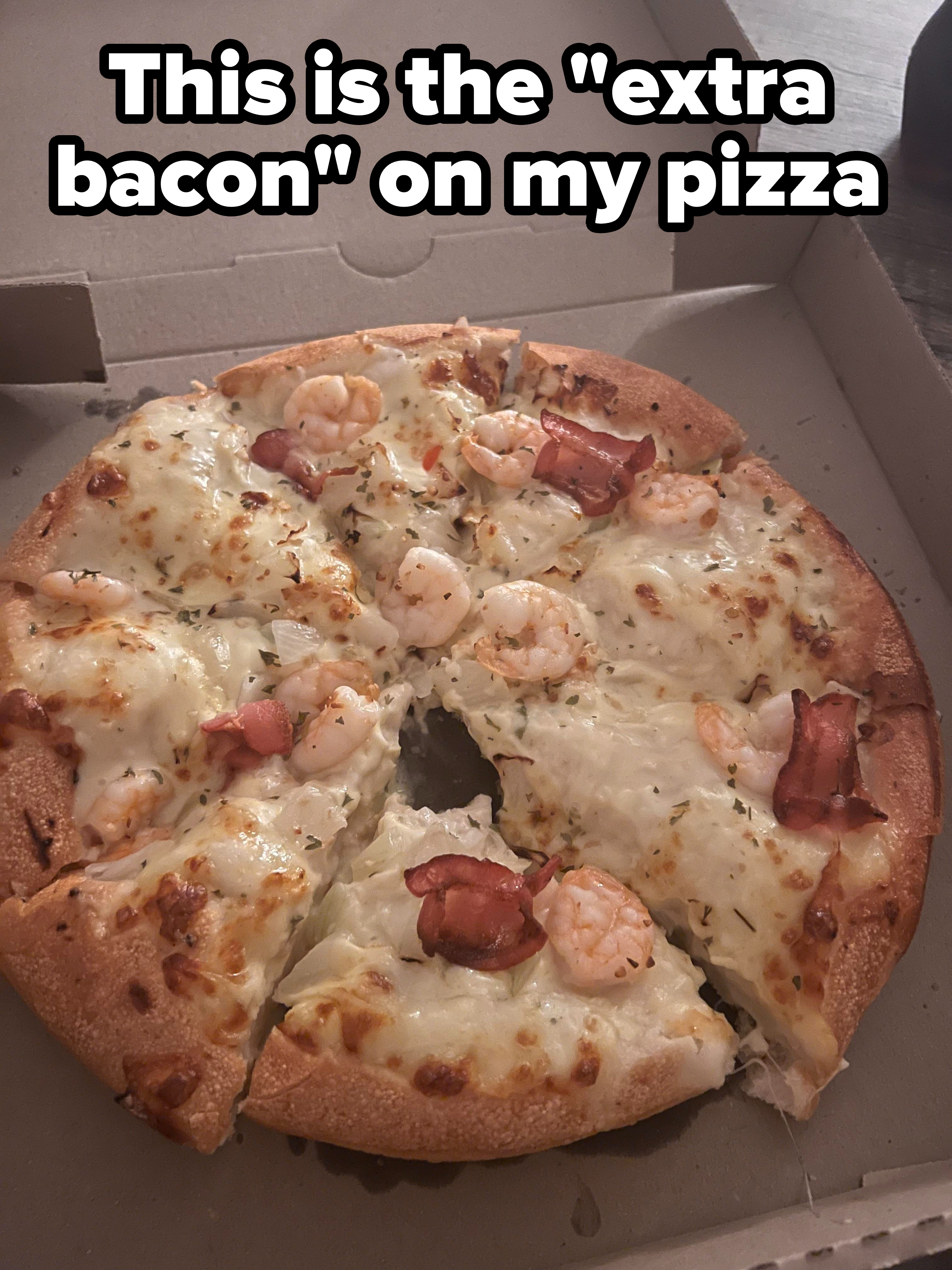A pizza with shrimp and about three small curled pieces of bacon