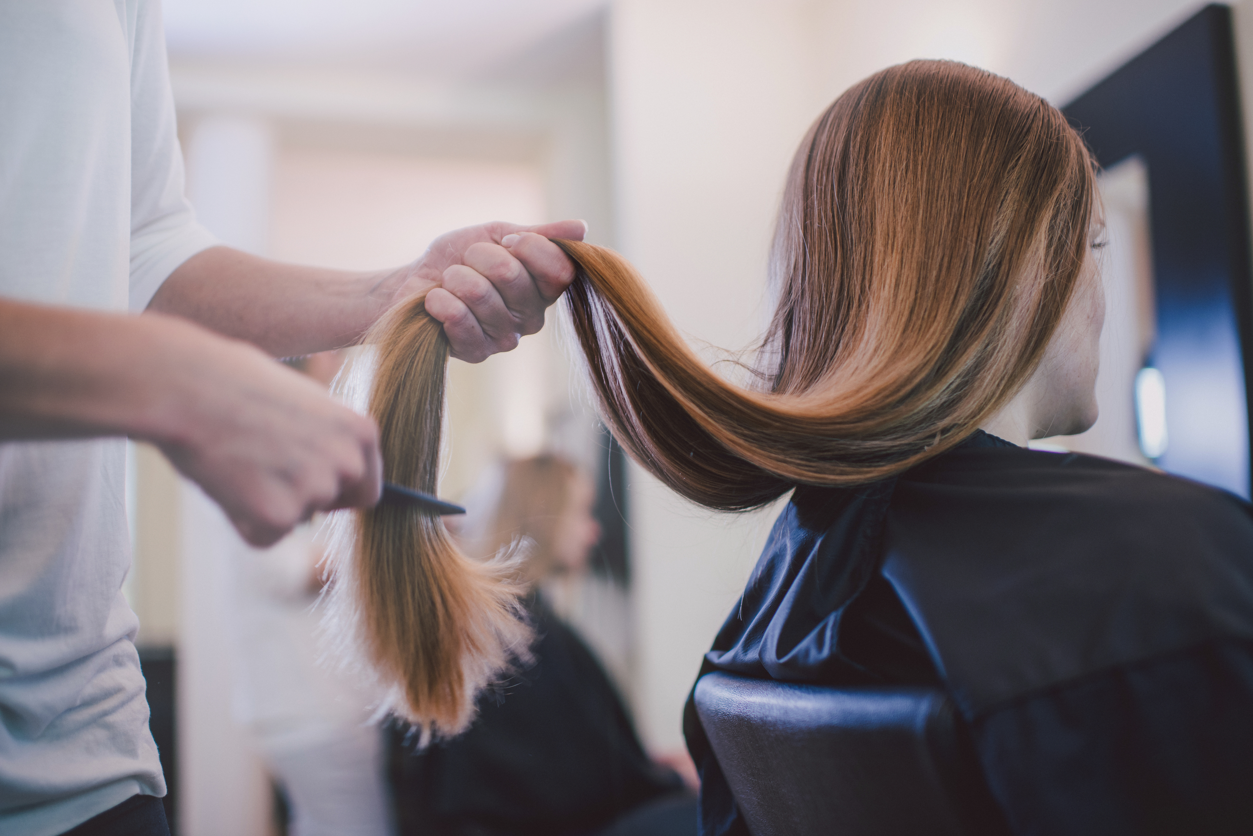 A person brushing a client&#x27;s long hair